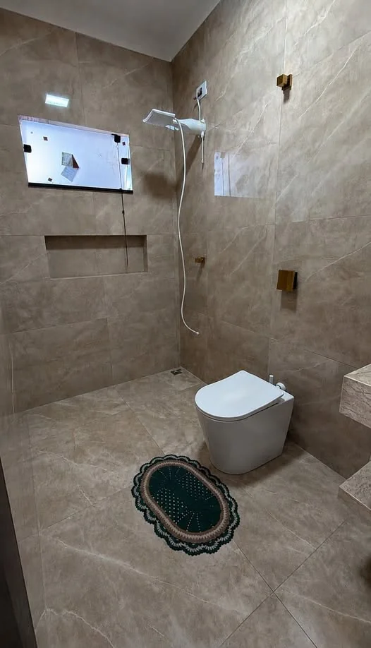 Banheiro revestido com porcelanato bege marmorizado no piso e nas paredes.