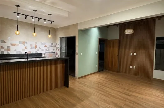 Cozinha e sala integradas, com bancada em ripado e piso amadeirado.