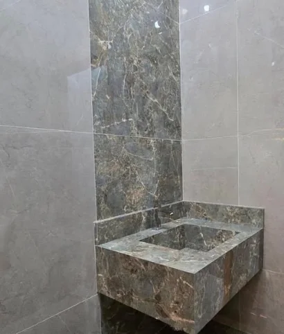 Lavabo com revestimento de parede e cuba em pedra escura.