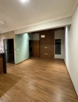 Sala ampla com piso amadeirado e parede em ripado.
