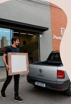 Cliente carregando uma caixa de porcelanato até a caminhonete na frente da loja